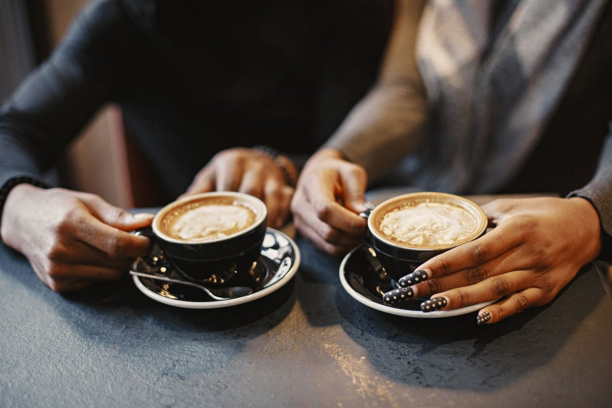 A couple's hands holding coffee cups at a table
